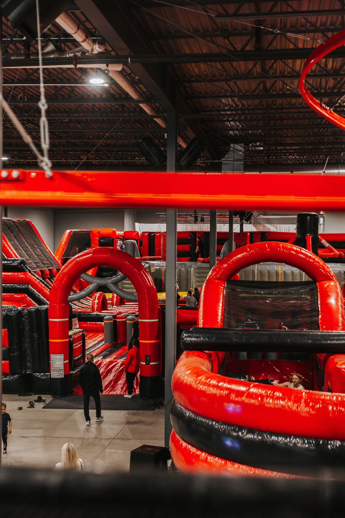 Vue panoramique des attractions intérieures de Ninja Factory, incluant les parcours d’obstacles et les structures gonflables.